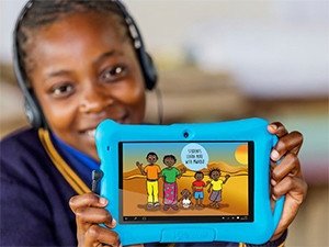 A young South African girl smiling while holding a blue educational tablet